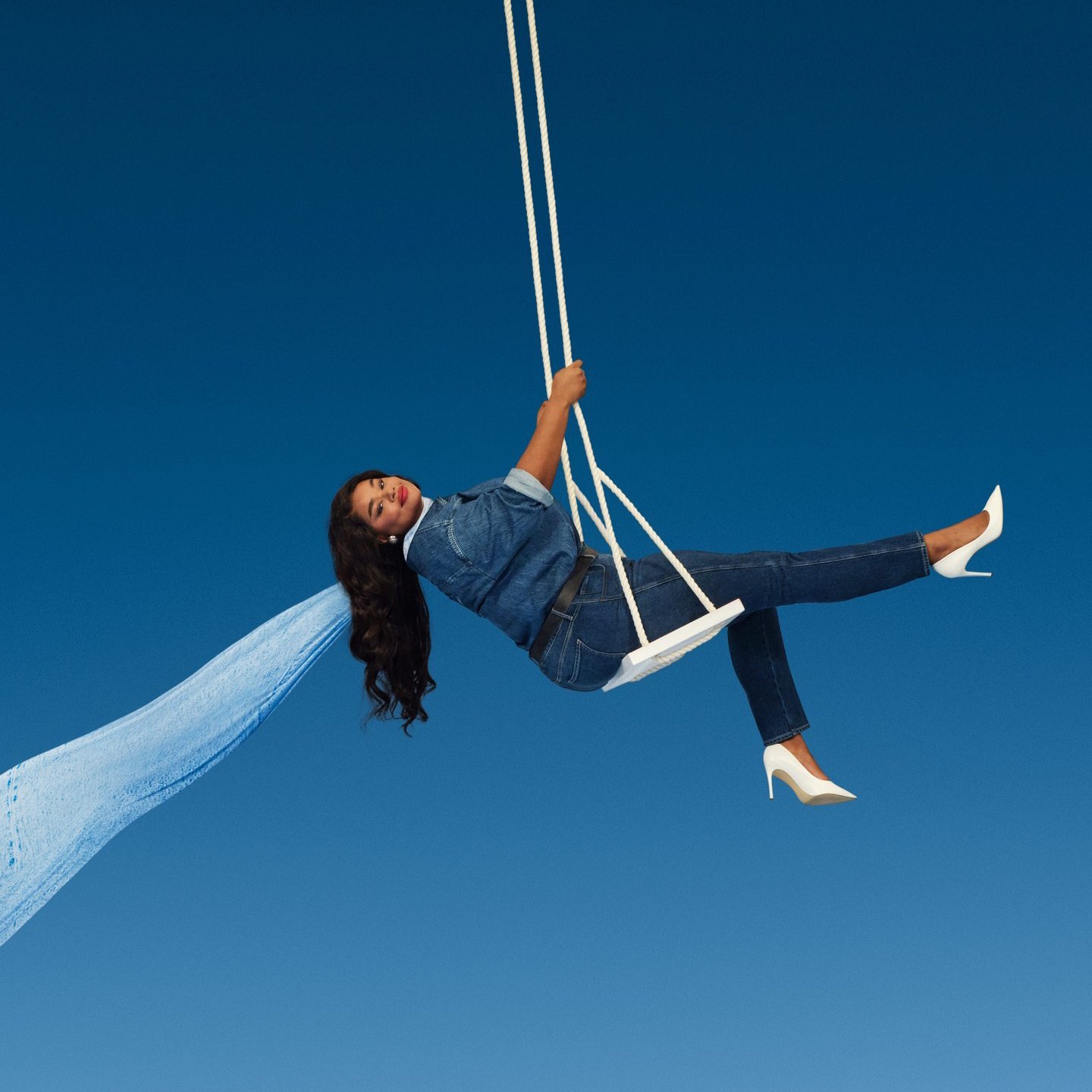 Old Navy woman on swing against blue sky and jet trail